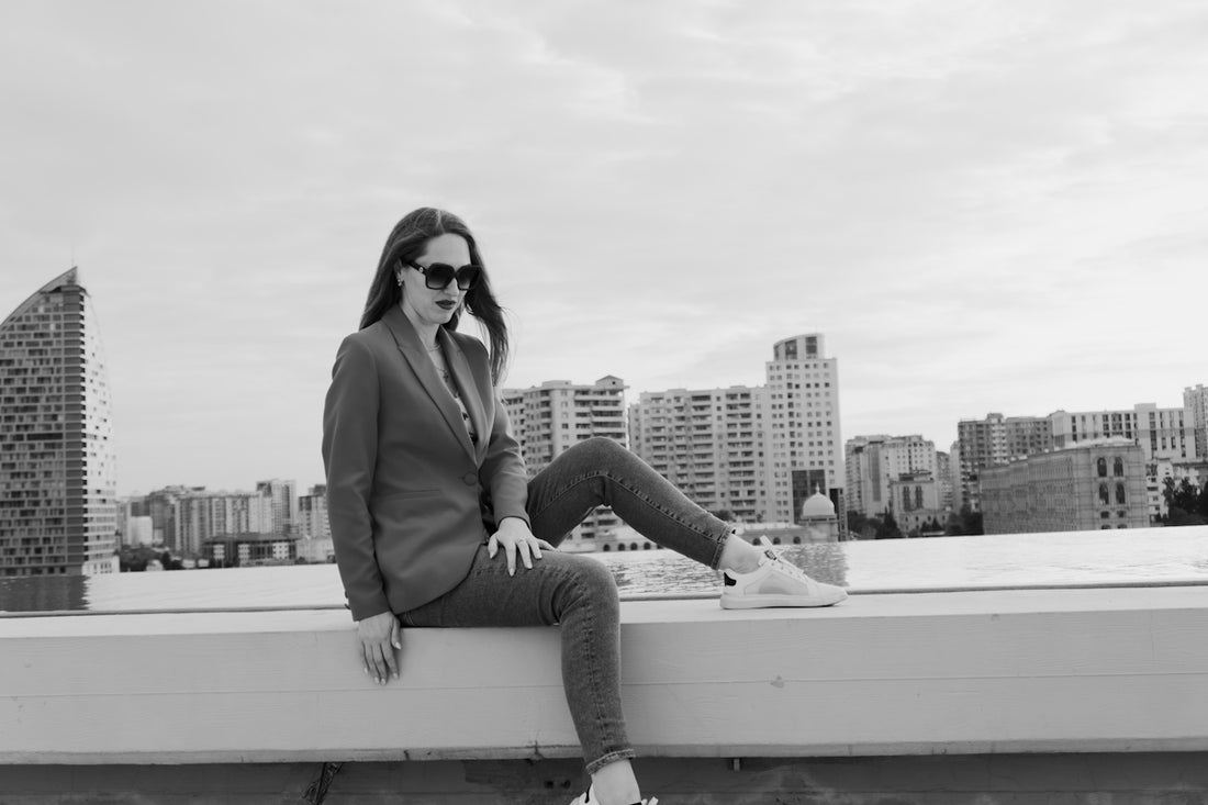 Woman in suit sitting on a ledge with cityscape background